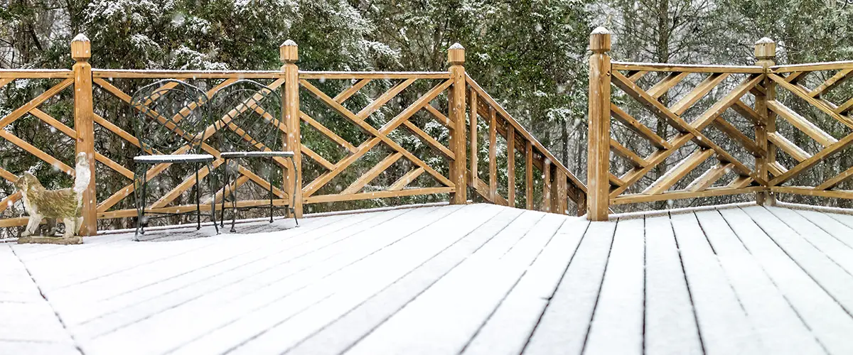 A wooden railing on a deck in the snow