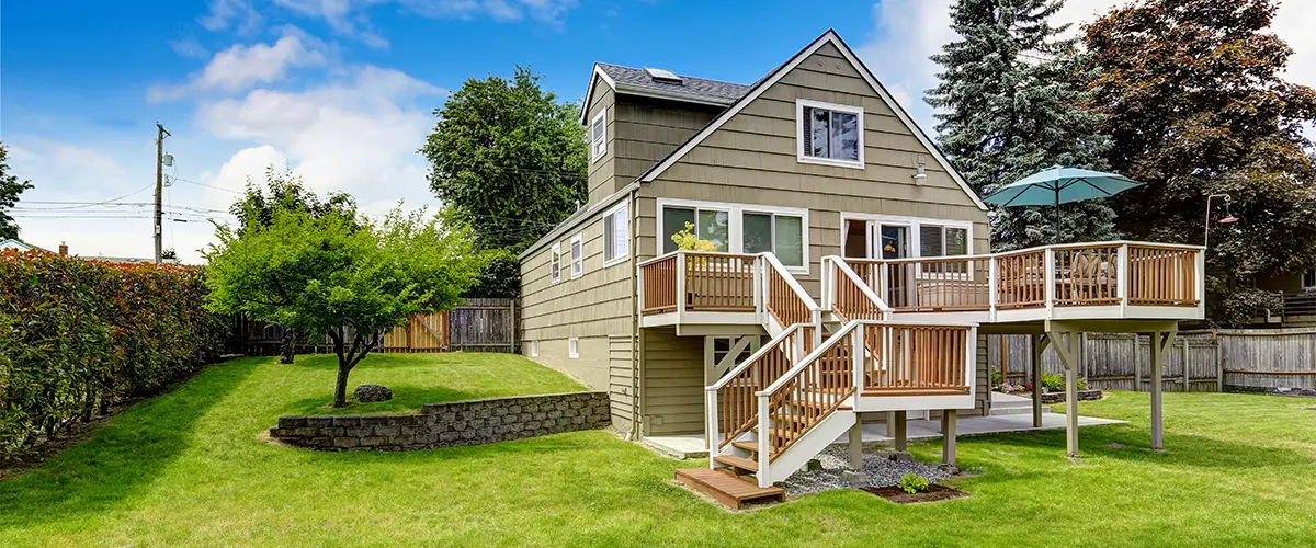 A large, two-levels deck attached to a house on a patch of grass