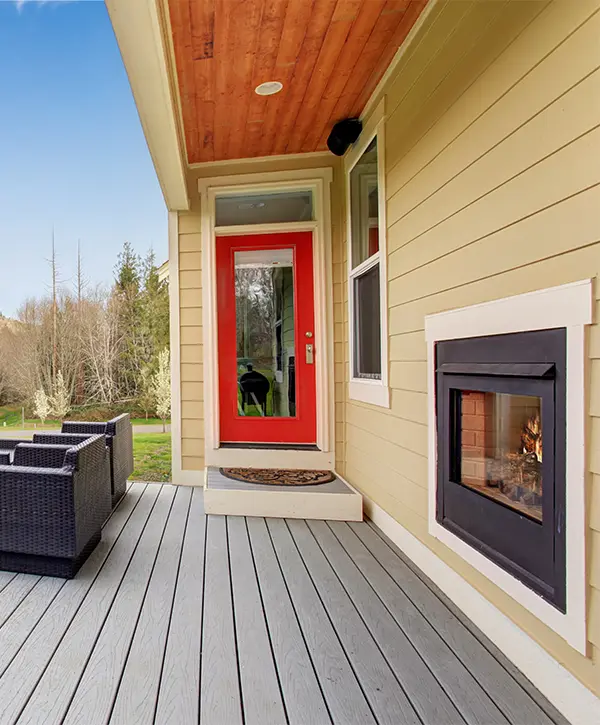 Composite decking around a beige home with a red door