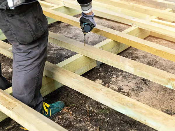 A pressure-treated wood deck frame being installed