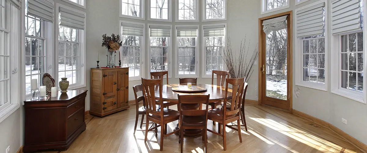 A beautiful sunroom with wood flooring and furniture in the winter