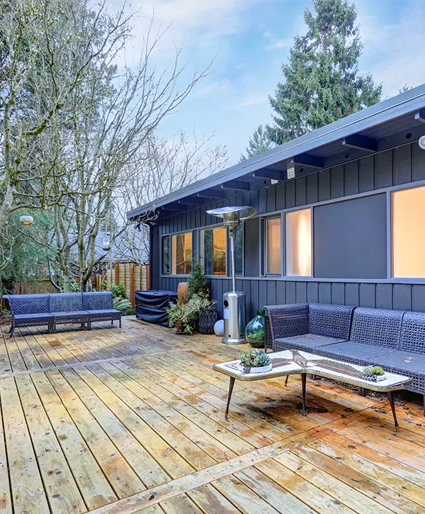 A wood deck with outdoor furniture and a dark gray home