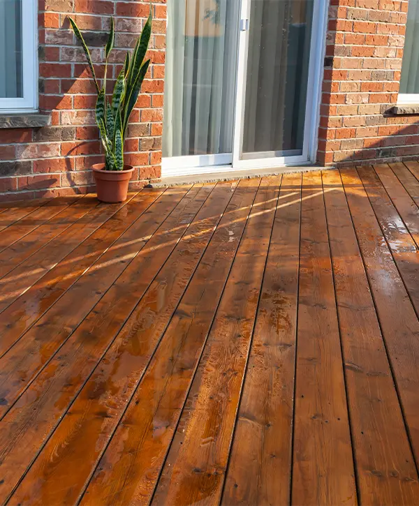 A cedar decking with around a brick home and a plant