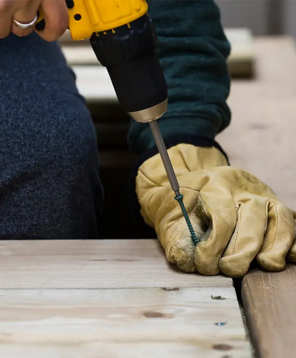 A deck builder installing decking with screws