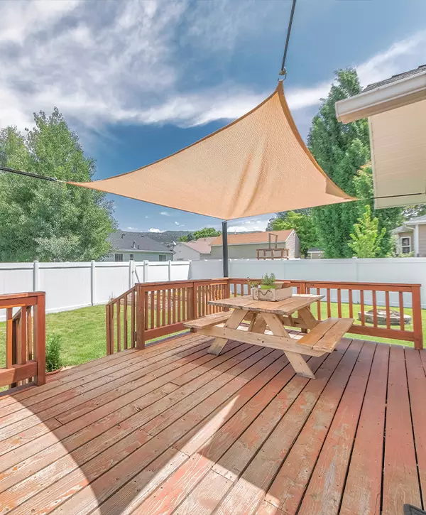 Wooden deck with deck railing in Omaha with a sunshade over the table with bench seats