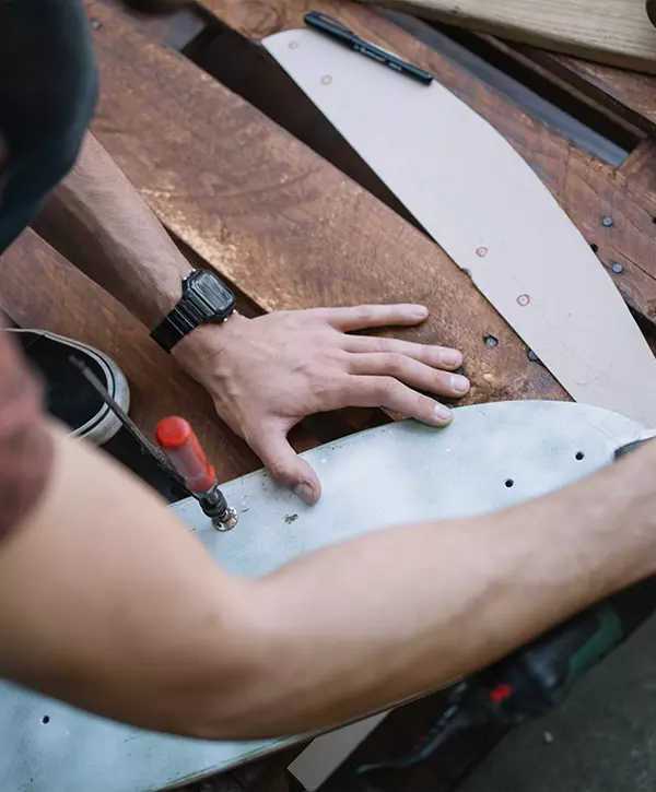 Top view of male hands polishing wooden board. Man's hands using sander and polishing wooden skateboard deck outdoor, Deck Repair In Council Bluffs IA