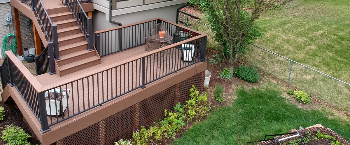 Elevated wooden deck with modern underpinning, lush garden, and stairs in a residential area.