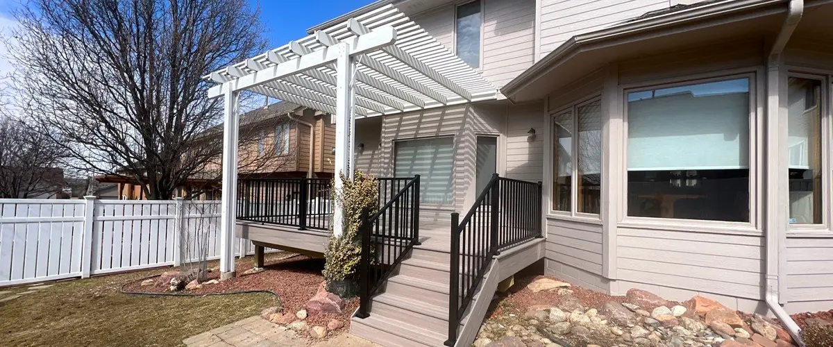 Modern deck installation with white pergola and landscaped garden in suburban home.