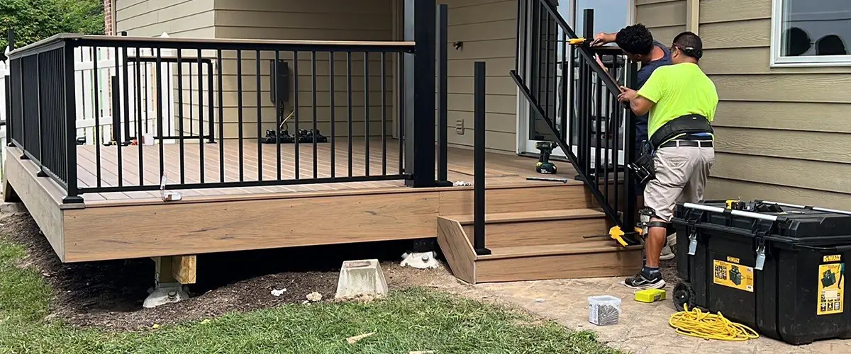 Worker securing railing post on wooden deck during footing installation in Omaha, NE.