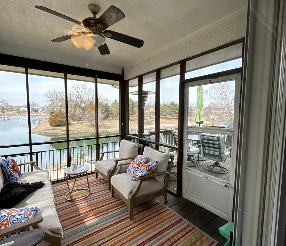 a screened in porch built by Deck Bros in Omaha, with rugs and doutdoor furniture