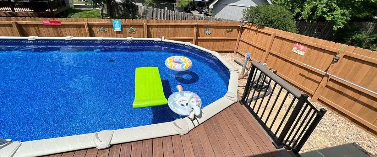 Above-ground pool with inflatable floats in a fenced backyard on a sunny day. Pool Deck Resurfacing In Omaha, NE