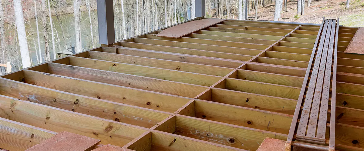 An newly constructed layout of flooring joists inside new custom built home with wooden deck patio