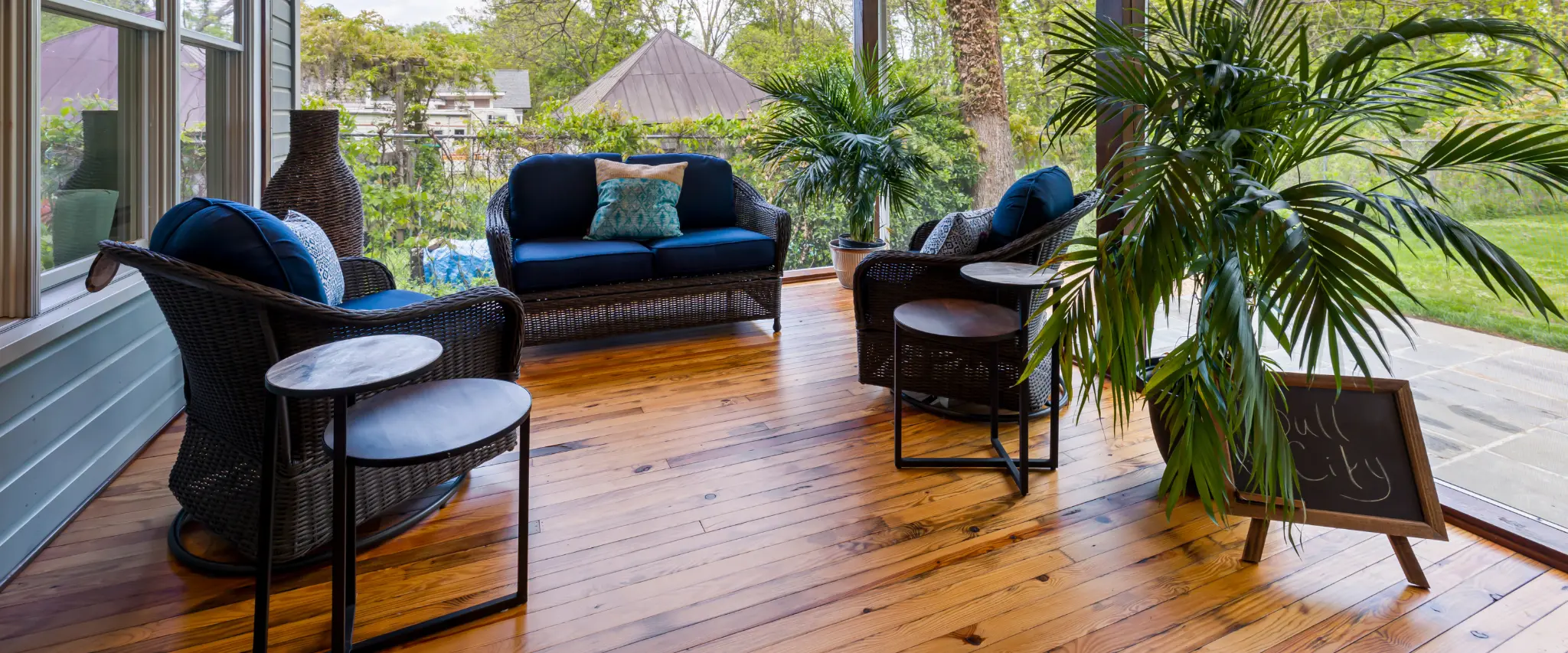 Cozy outdoor seating area with wicker furniture and plants on a wooden deck