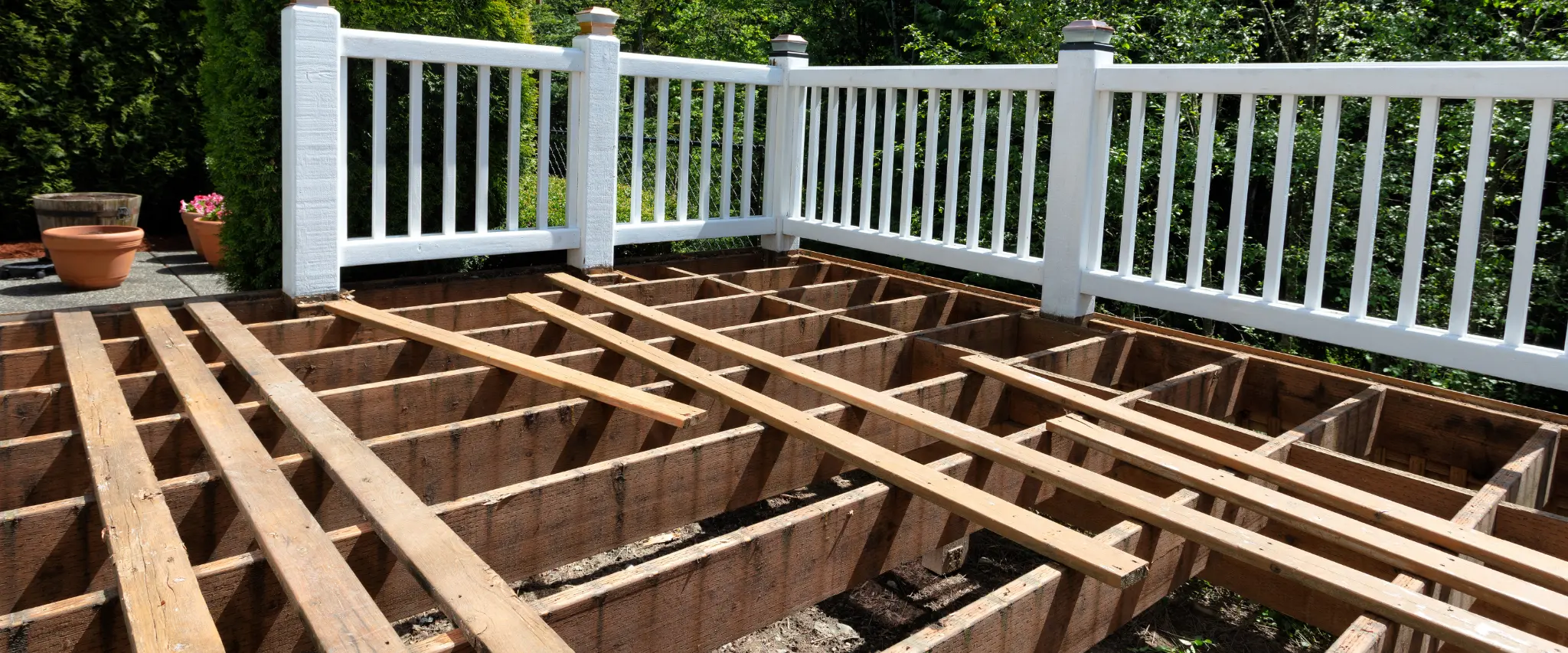 Close-up of deck under construction with wooden framing and white railing installed