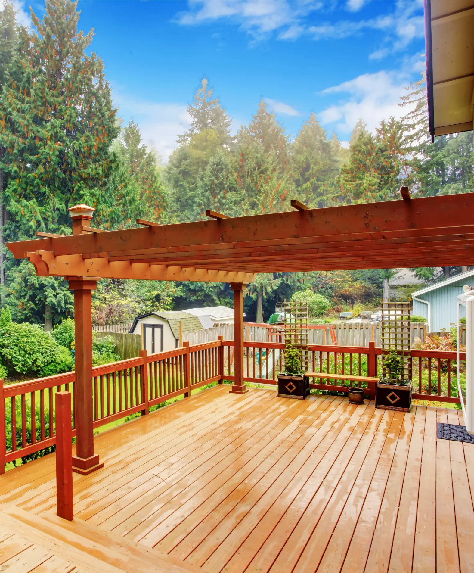 Stunning deck with a wooden pergola and beautifully landscaped garden in the background