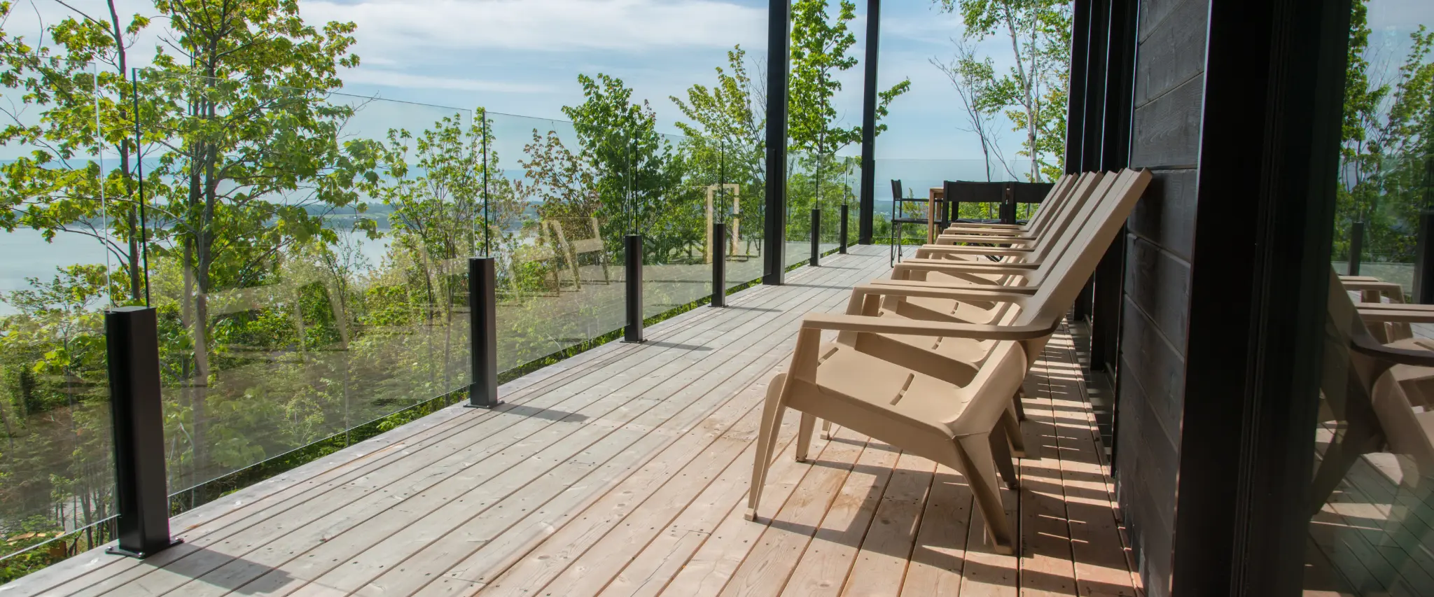 Modern deck with glass railings and chairs, providing an unobstructed view of the outdoors