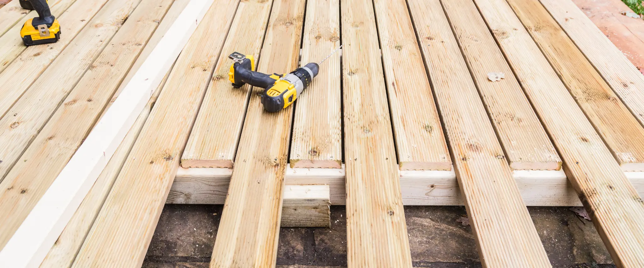 Wooden deck under construction with drills and tools laid out for the next phase of building