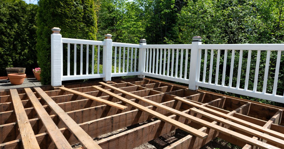 Unfinished deck framework with wooden joists and white railings