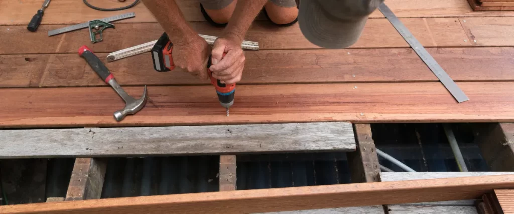 Worker using a drill to secure deck boards onto the frame