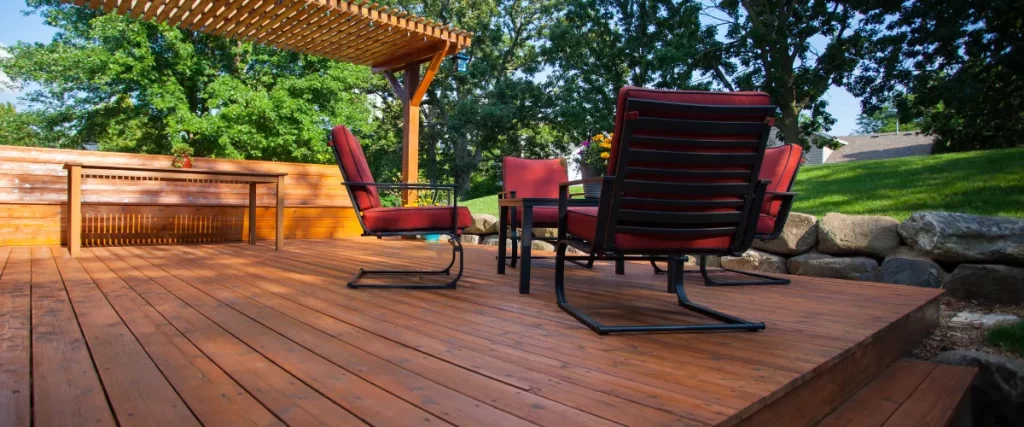 Outdoor deck with a pergola, red cushioned chairs, and a wooden table