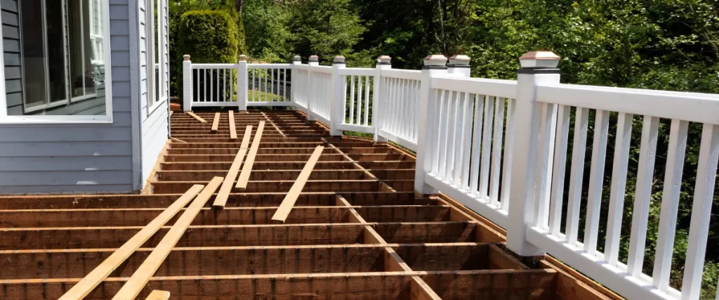 Partially constructed deck frame with white railing in a backyard