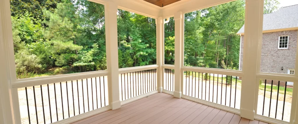 Covered porch with white railings overlooking a lush backyard