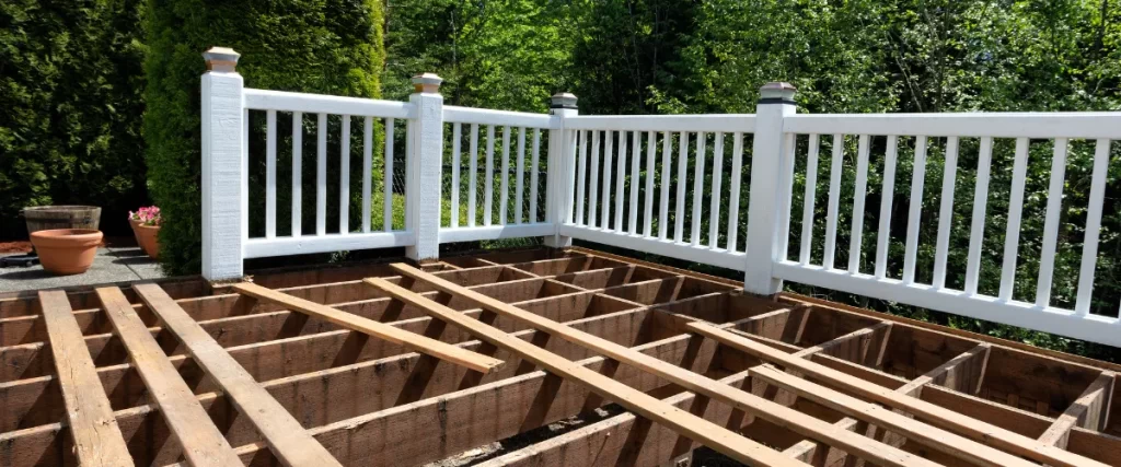 Partially constructed deck with exposed wooden framing and white railings