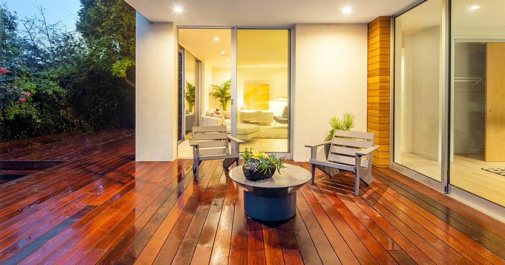Reclaimed Wood for Decks: A Beautiful and Eco-Friendly Choice Luxurious modern patio with wet reclaimed wood decking and outdoor furniture, blending indoor and outdoor living spaces.