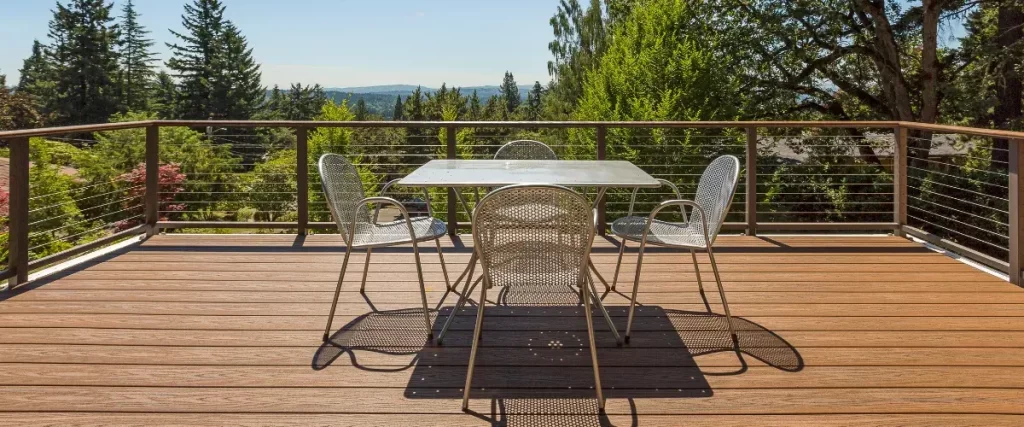 Modern composite deck with metal railing and outdoor dining set overlooking scenic landscape. Ideal for durable, low-maintenance decking.