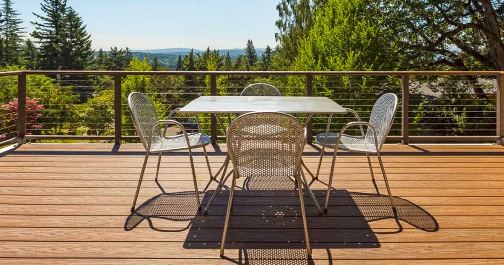 Aluminum Decks vs Composite Decks: Which One is Right for You? Modern composite deck with metal railing and outdoor dining set overlooking scenic landscape. Ideal for durable, low-maintenance decking.
