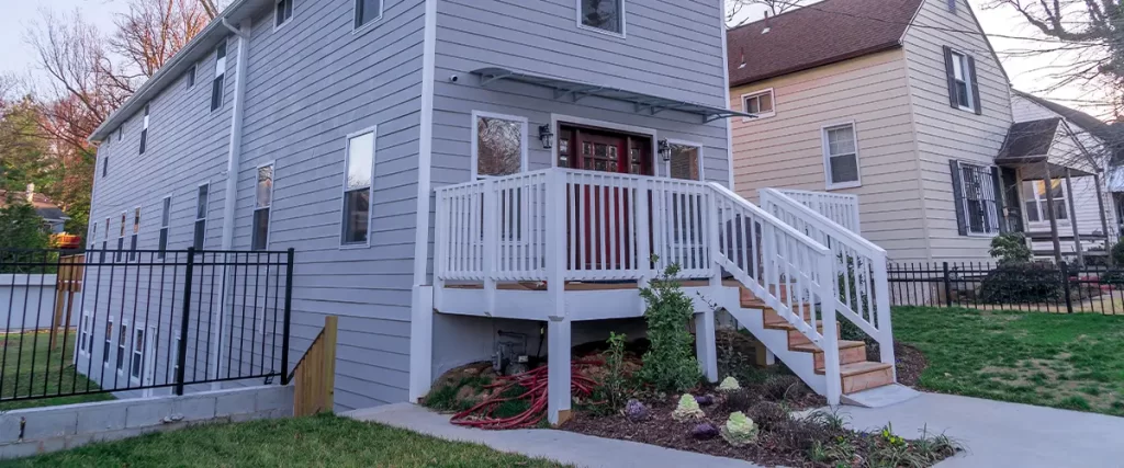 Modern gray home with a white-railed front porch and stairs leading to the entrance.