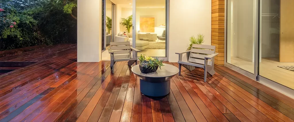 Luxurious modern patio with wet reclaimed wood decking and outdoor furniture, blending indoor and outdoor living spaces.