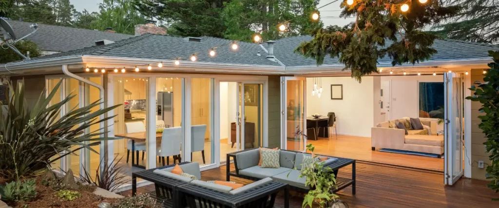 Another view of the same cozy backyard patio with outdoor furniture, fire pit, and string lights, slightly different angle.