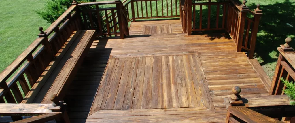 Medium-toned wooden deck with a patterned plank design and railing.