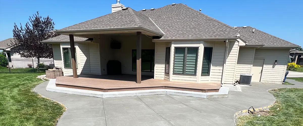 Covered Deck Builder in Lincoln, NE Backyard covered deck with raised composite platform and curved concrete patio for outdoor entertaining