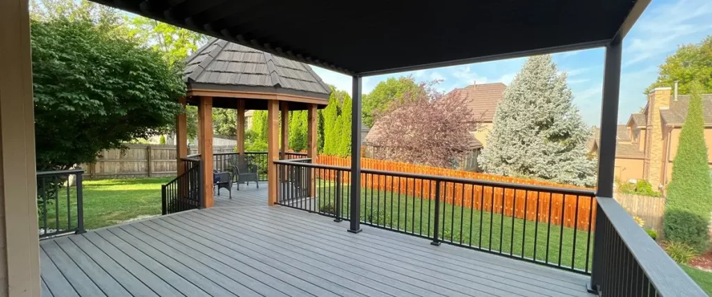 How to Deal With Algae Growth on Shady Decks Composite covered deck with black railing and attached gazebo in a landscaped backyard with privacy fence