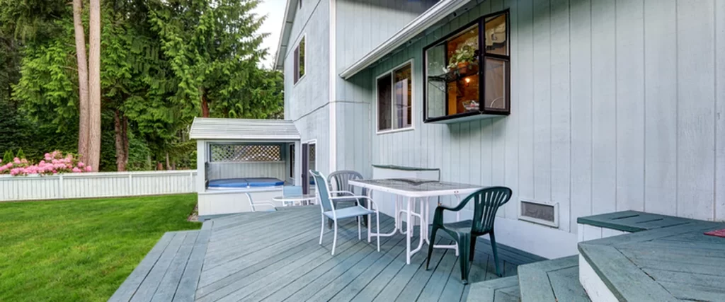 Deck Trends in Lincoln for 2025: Colors, Features, and Materials deck trends lincoln ne gray wooden deck with patio furniture surrounded by lush greenery