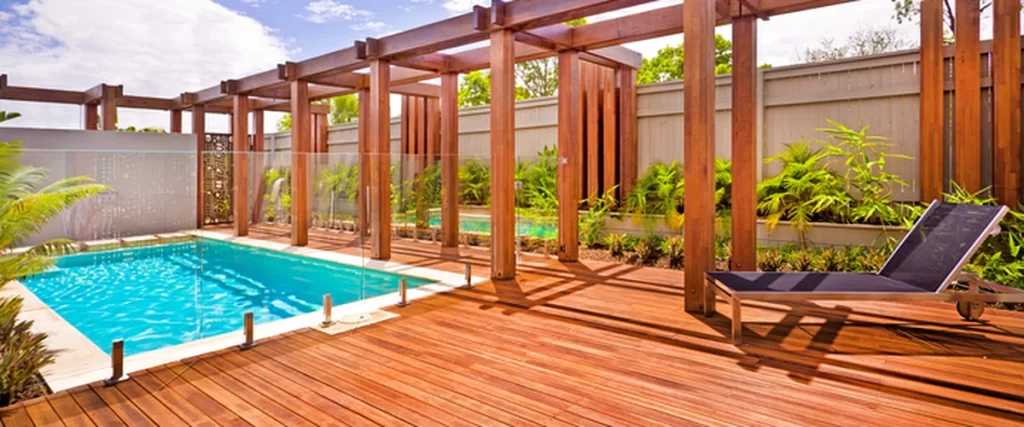 Deck Trends in Lincoln for 2025: Colors, Features, and Materials deck trends lincoln ne plaintext modern wooden deck with pergola glass pool fencing and poolside lounge