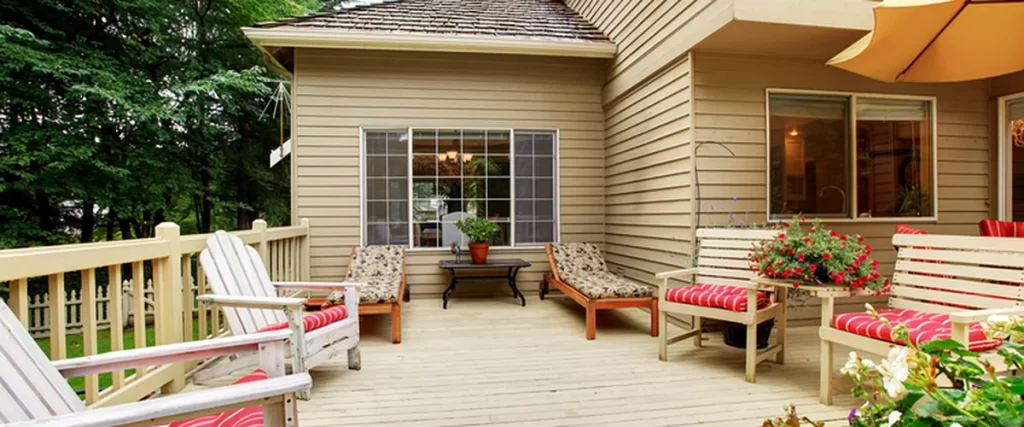 Deck Trends in Lincoln for 2025: Colors, Features, and Materials deck trends lincoln ne spacious wooden deck with red cushioned seating beige siding and vibrant flowers