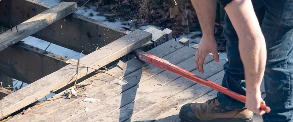 Lincoln Homeowners’ Guide to Preparing Your Deck for Winter lincoln ne professional contractor using crowbar to expertly remove damaged wooden deck planks