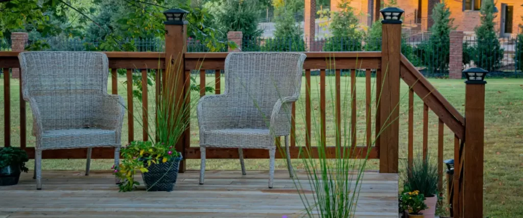 A deck featuring a wooden railing with vertical balusters and post cap lights