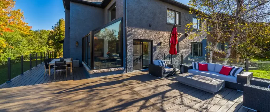 a modern outdoor living area featuring a large wooden deck and a sunroom extension