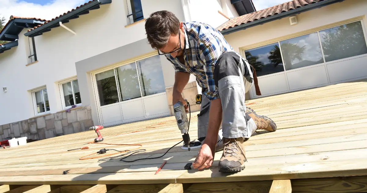 a person performing deck maintenance using power tools outdoors