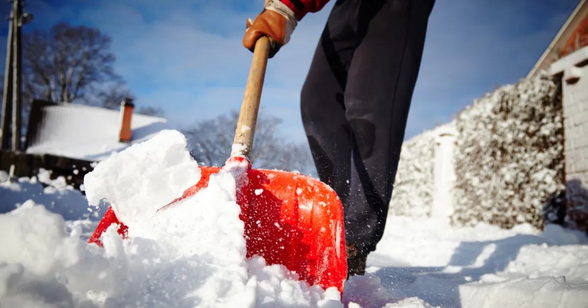 a person using a traditional snow shovel to clear snow from an outdoor area