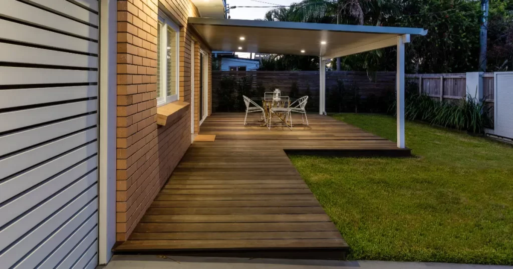 an outdoor wooden deck attached to the side of a brick house