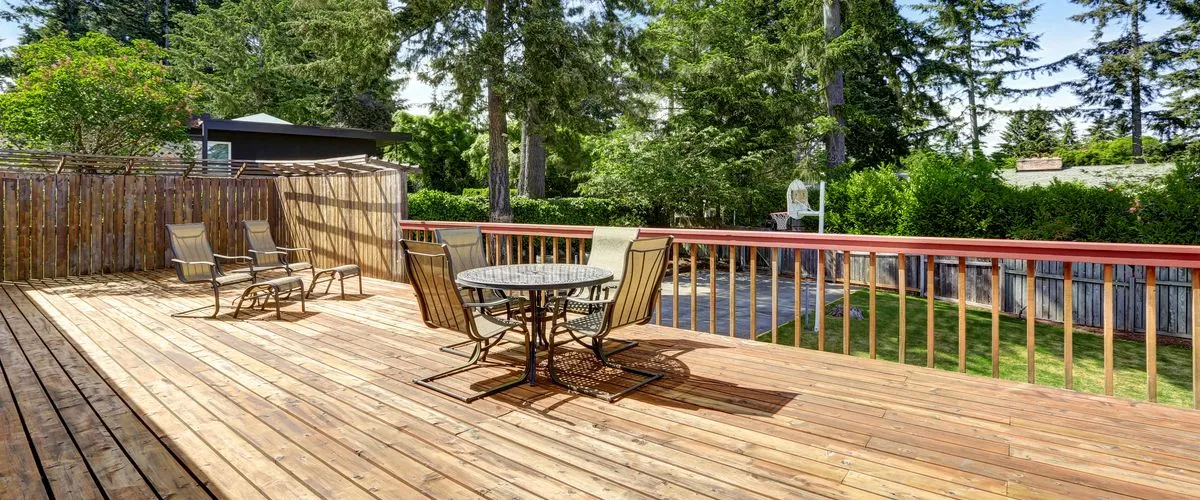 Spacious wooden deck featuring a round dining table with four chairs and a lounge area with reclining seats.