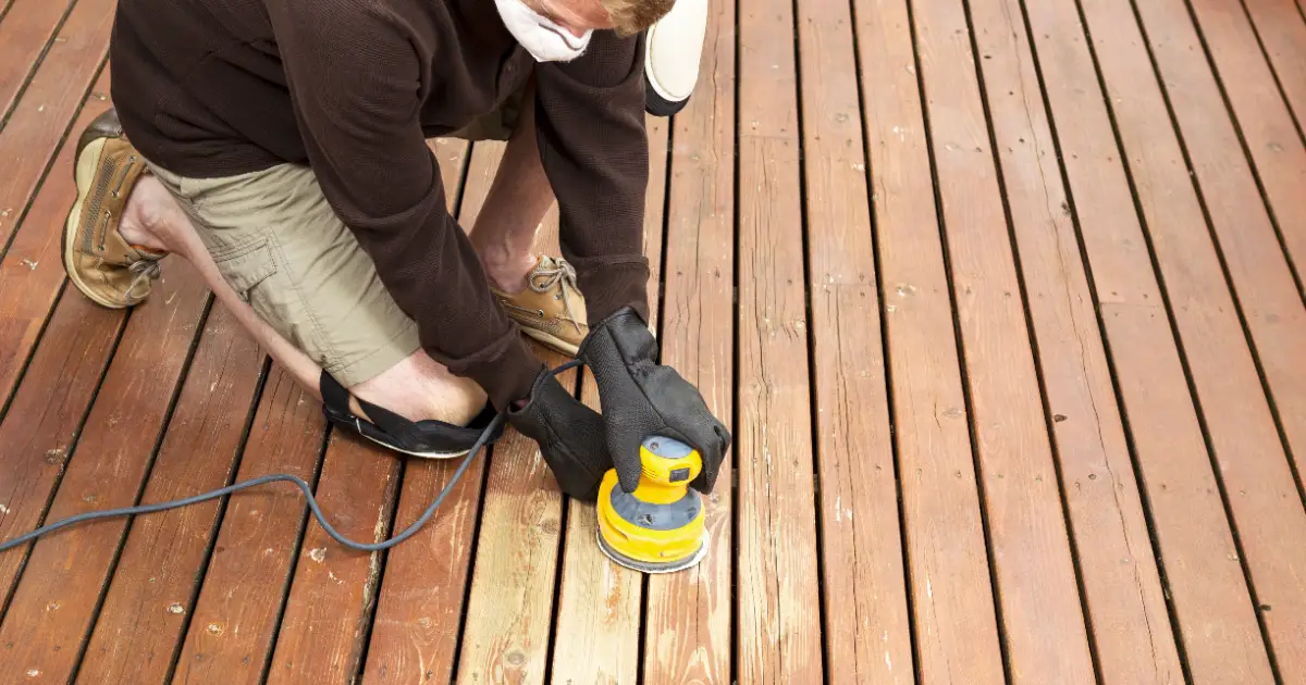 a person using an orbital sander to refinish a wooden deck