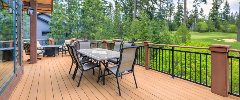 an elevated outdoor wooden or composite deck attached to a house, featuring an outdoor dining area and views of a natural, possibly golf course, landscape