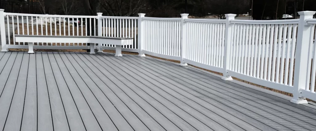 an outdoor deck constructed with composite decking material and white vinyl railings