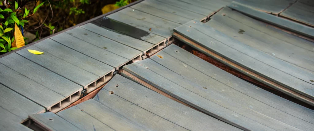 Protecting Your Deck From Hail in Eastern Nebraska High angle view of gray weathered and damaged deck boards showing structural cracks and misalignment.